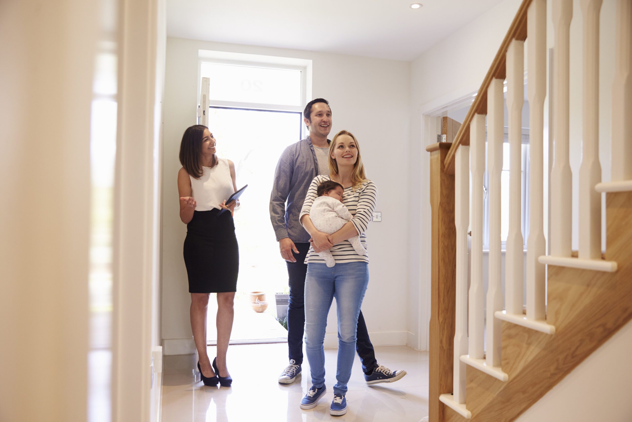 Real Estate Agent Showing Young Family Around Property For Sale